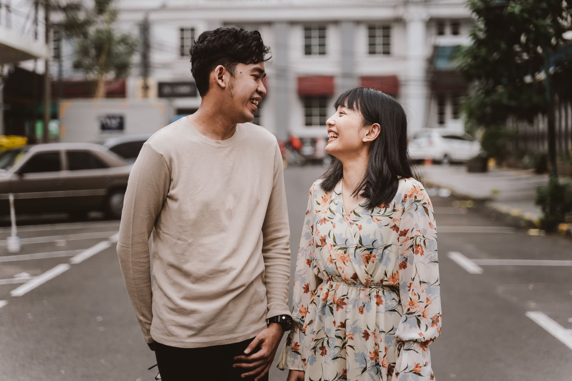 Pasangan muda Indonesia tertawa bersama di jalan kota